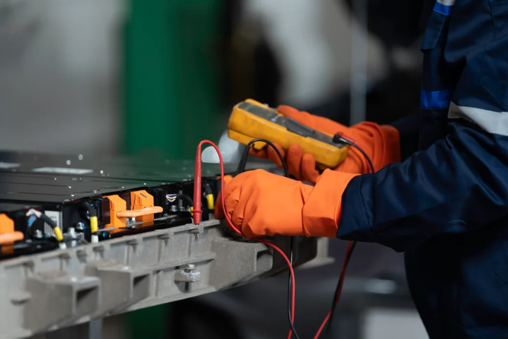 Electrician testing equipment with a multimeter during preventive maintenance